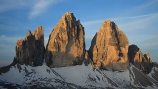 The Three Peaks or Tre Cime for which the Dolomites are known. The three peaks are radiated from the sun before the blue sky.
