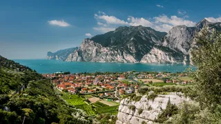 Beautiful places in Italy: view from above to a city on Lake Garda with turquoise blue water and the mountains in the background.