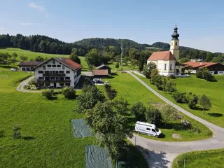 Air intake from a farm and a church in a small village with parked camper.