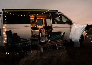 A camper is there at night. It is decorated with light chains.