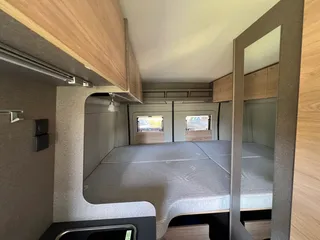 Schlafbereich im Kastenwagen mit einer zweiteiligen Matratze im Heck und Blick auf die oberen Staufächer.