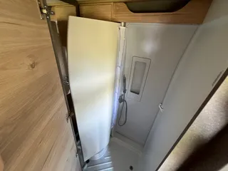Kompaktes Bad im Campervan mit moderner, geschlossener Duschkabine und integrierter Duscharmatur für komfortables Reisen.