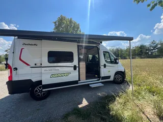 Komplettes Seitenprofil des Kastenwagens unter blauem Himmel mit aufgestellter Sonnenmarkise.