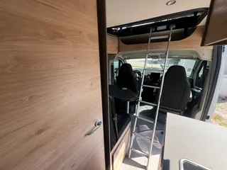 Campervan mit Küchenzeile und einer stabilen Aluminiumleiter, die in das obere Aufstelldach führt.