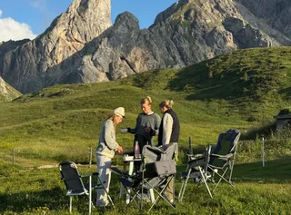 Freunde bereiten Frühstück auf einem Hügel mit den Dolomiten im Hintergrund zu